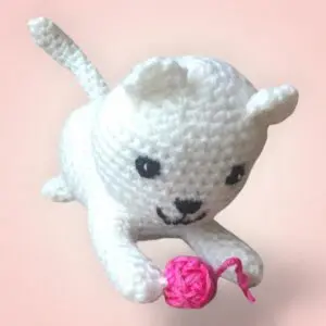 Adorable chat blanc en crochet avec une balle rose.