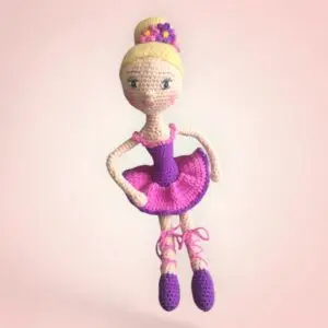 Gracieuse poupée danseuse en crochet avec une robe rose et violette.