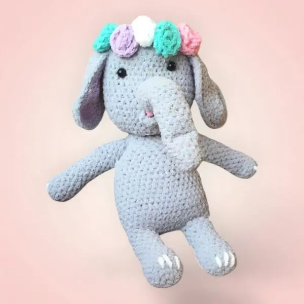Charmant éléphant en crochet avec une couronne de fleurs.