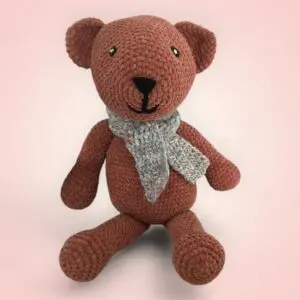 Adorable ours en crochet avec une écharpe grise.