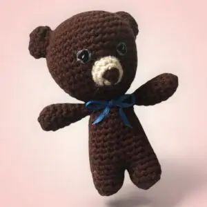 Adorable petit ours en crochet avec un nœud bleu.