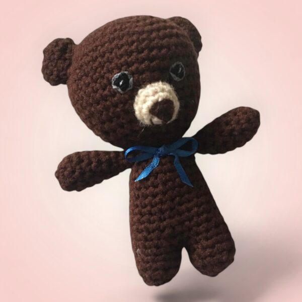 Adorable petit ours en crochet avec un nœud bleu.