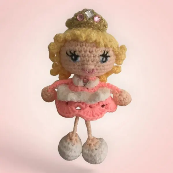Poupée crochetée avec une couronne et une robe rose.