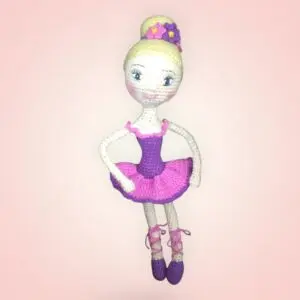 Charmante poupée ballerine en crochet, vêtue d'une robe rose et violette.