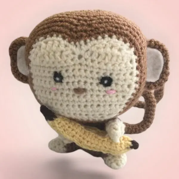 Adorable singe en peluche tenant une banane, fait main avec amour.