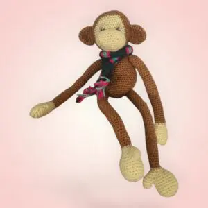 Singe en crochet avec une écharpe colorée.