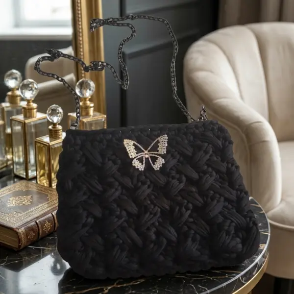 Sac à main noir avec broche papillon.